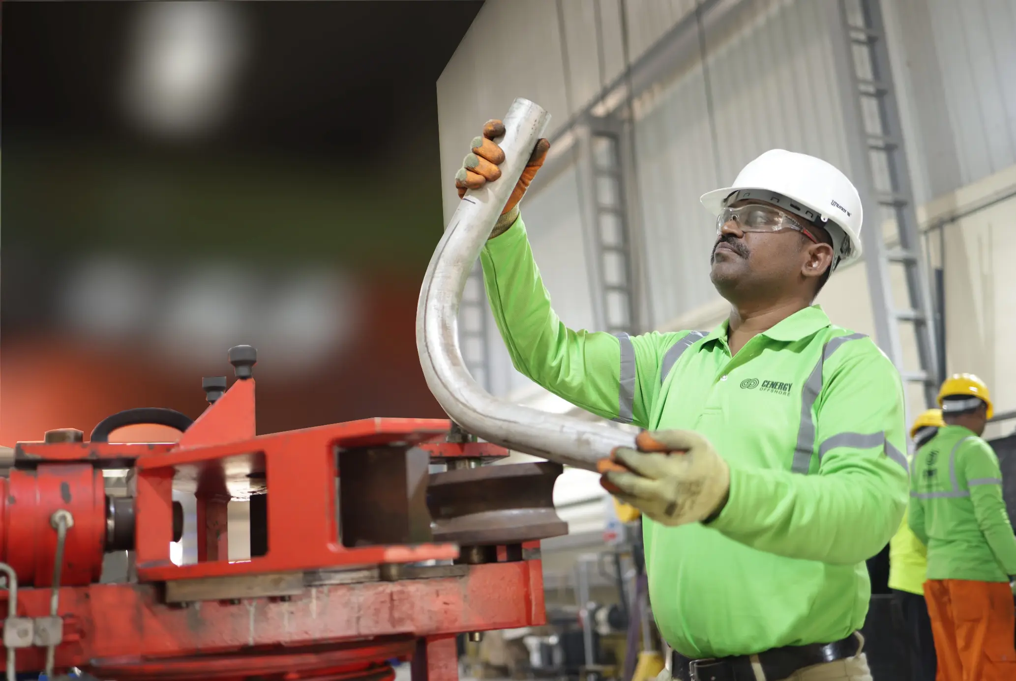 cenergy offshore personnel in workshop holding a pipe elbow